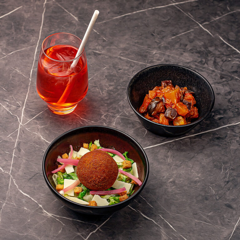 Menu composé d'un arancini volaille fromage sur un lit de salade, d'une part de ratatouille et d'une boisson de sirop à l'eau