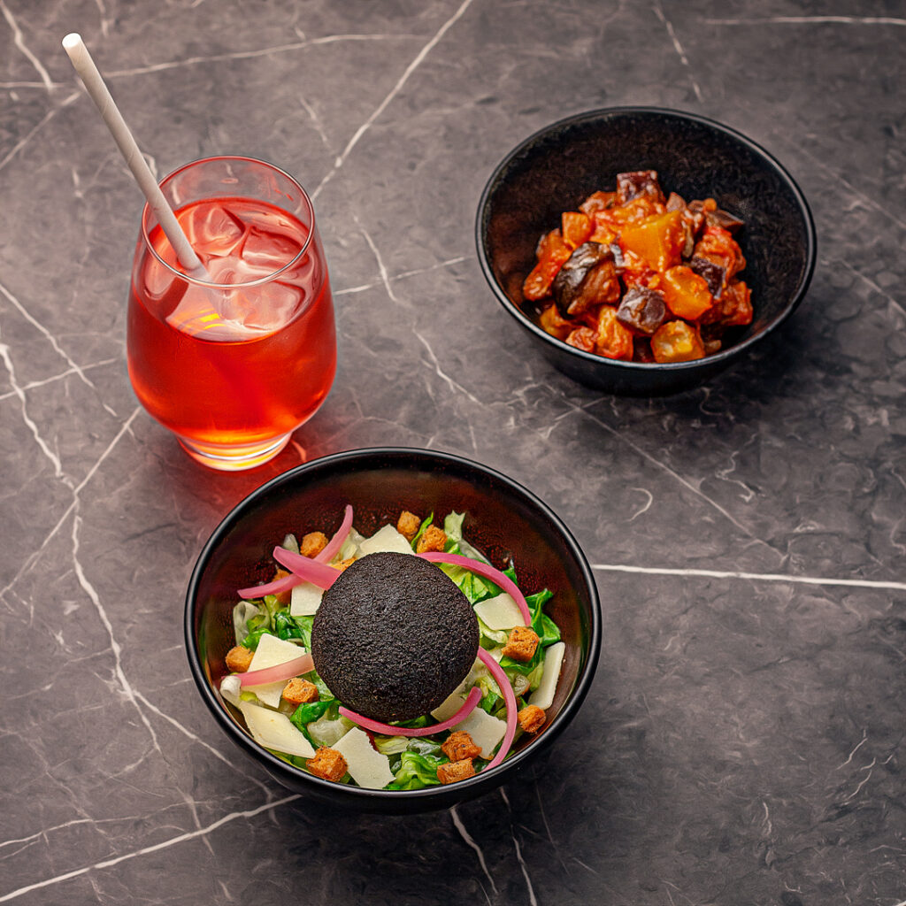 Menu composé d'un arancini volaille saté sur un lit de salade, d'une part de ratatouille et d'une boisson de sirop à l'eau
