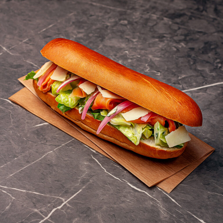 Pain garni complet, composé de laitue romaine finement ciselée, émincé de truite fumée, copeaux de parmesan, oignons marinés (pickles), et son incontournable sauce Grand-Mer à base de citron et d’aneth.